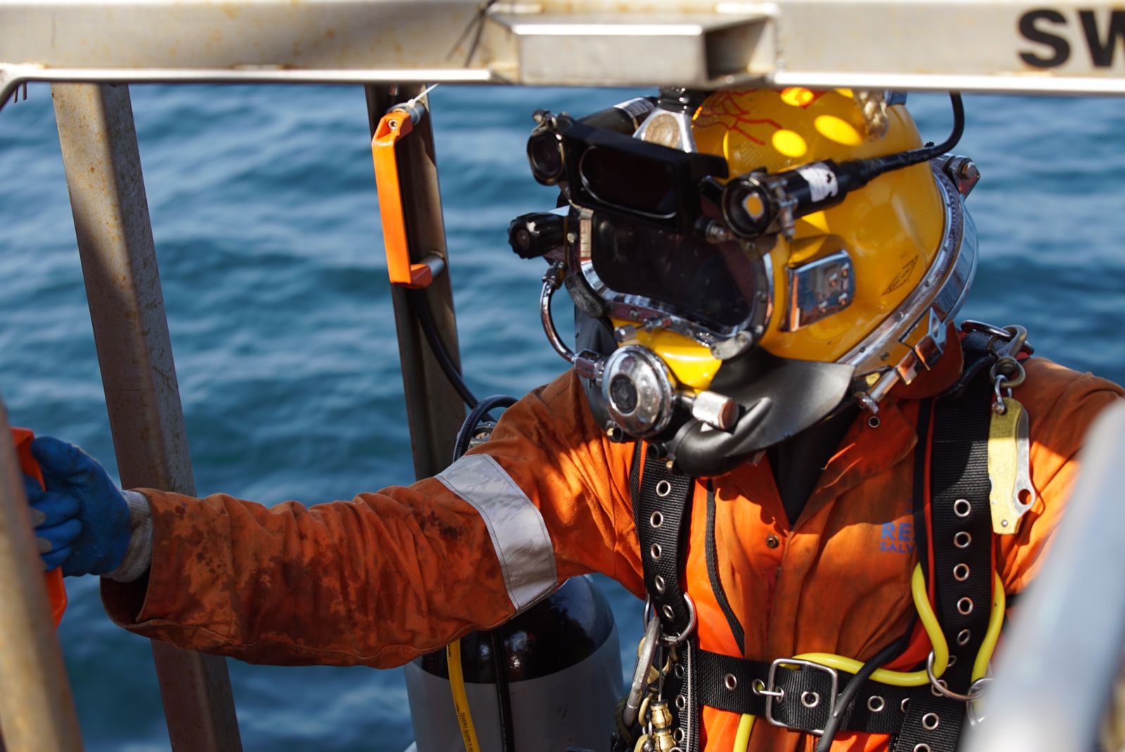 Diver climbing out of the water with dive helmet on.