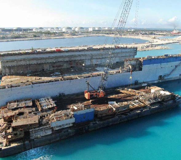 A barge docked to a dry dock with bright blue water in the background